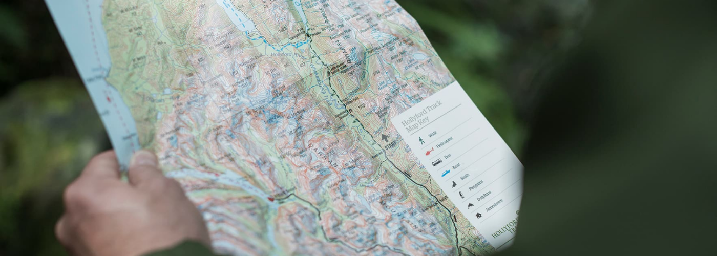 Person holding Hollyford map 1400 x 500